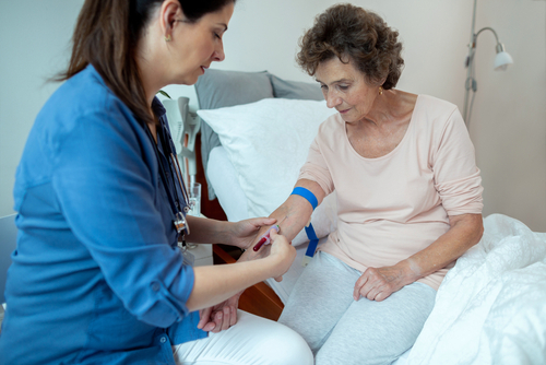 A phlebotomist drawing blood from a seated patient